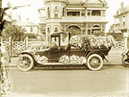 Photograph of a hearse decorated with flowers.